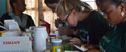 Medication is prepared to be dispensed among local Tanzanian patients during a healthcare outreach. A group of Public Health volunteers prepare medication for distribution under supervision in Tanzania.